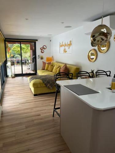a kitchen and living room with a yellow couch at Chiswick Garden Studio with Outdoor Pool and Boutique Finish in London