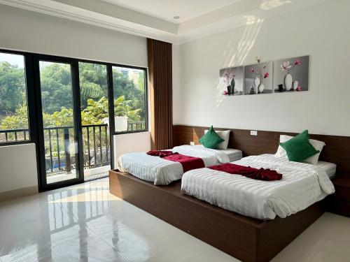 a bedroom with two beds and a large window at De' Mon Villa in Làng Tong Tchoung