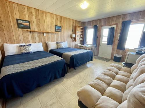 a hotel room with two beds and a couch at Chalets Camping Bernatchez in Mont-saint-pierre