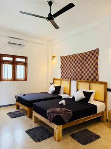 a bedroom with two beds and a ceiling fan at Edwin's Ahangama in Ahangama