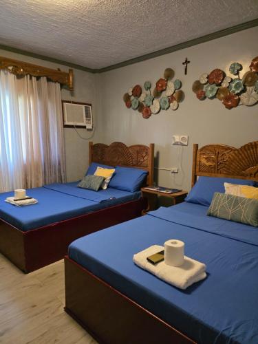 a bedroom with two beds with blue sheets and a cross on the wall at La Leona Homestay in Hernani