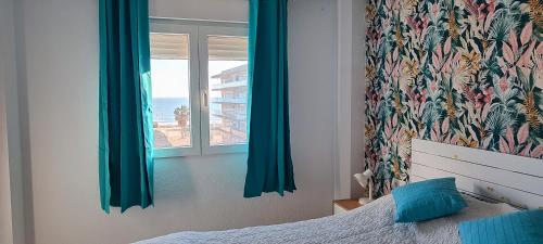 a bedroom with a bed and a window with blue curtains at Ocean front apartment Trianon in Daimuz