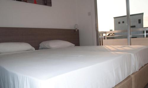 a large white bed in a room with a window at St. George Rent Rooms in Larnaka