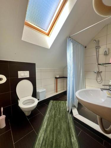 a bathroom with a toilet and a sink and a skylight at Adriana Guesthouse in Jezerce