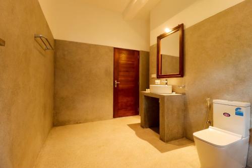 a bathroom with a toilet and a sink and a mirror at Haru Ahangama in Ahangama