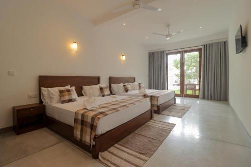 a large bedroom with two beds and a window at Haru Ahangama in Ahangama