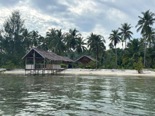 a small shack on a beach with palm trees at Ina Homestay in Mios Besar