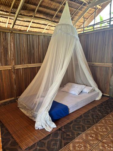 a bed in a room with a mosquito net at Ina Homestay in Mios Besar