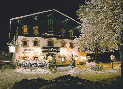 a house covered in christmas lights in the snow at Gasthaus Mitterjager in Kirchdorf in Tirol