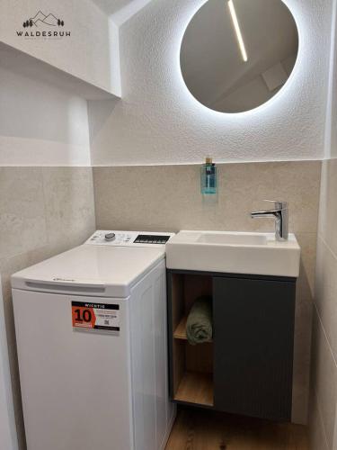 a white bathroom with a sink and a mirror at Waldesruh in Grünenbach