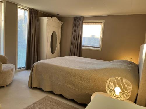 a bedroom with a bed and a chair and a window at Tuinverblijf Lauwersmeer in Anjum