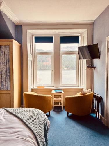 a bedroom with two chairs and a bed and a window at Lochwood House & The Wild Spa in Lochgoilhead