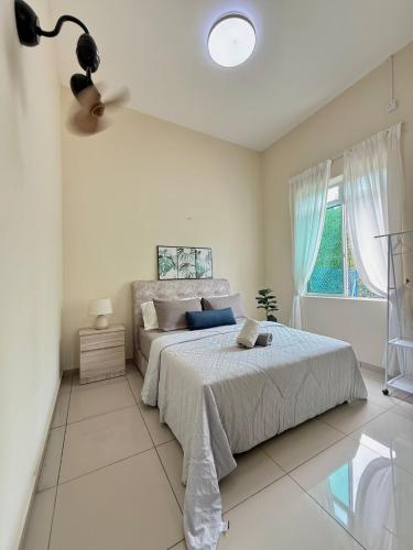 a white bedroom with a bed and a window at Jinta House Cherating in Kampong Baharu