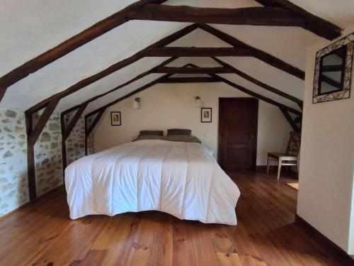una camera da letto con un letto grande in una stanza con pavimenti in legno di maison d'hôtes a Rouffiac