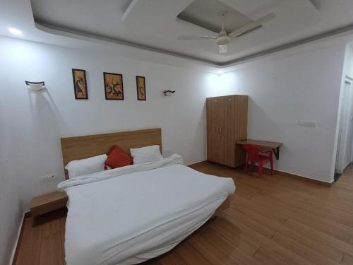 a white bedroom with a bed and a table at Prince Vatika in Alwar
