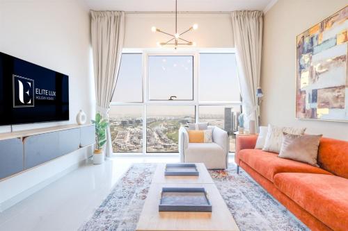 a living room with an orange couch and a tv at Elite LUX Holiday Homes - Serene Golf View Living 1 BHK in Damac Hills, Dubai in Dubai