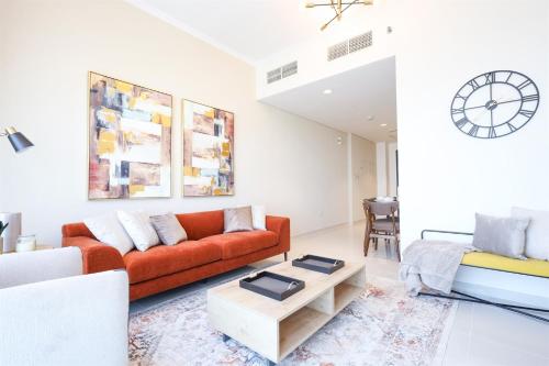 a living room with a red couch and a table at Elite LUX Holiday Homes - Serene Golf View Living 1 BHK in Damac Hills, Dubai in Dubai
