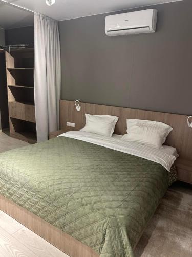 a bedroom with a large bed with a green blanket at Fisherman in Kyiv
