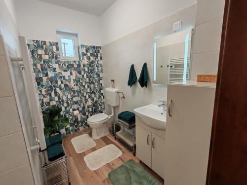 a bathroom with a toilet and a sink and a mirror at Bakonyi Vénkörte Vendégház in Bakonypéterd