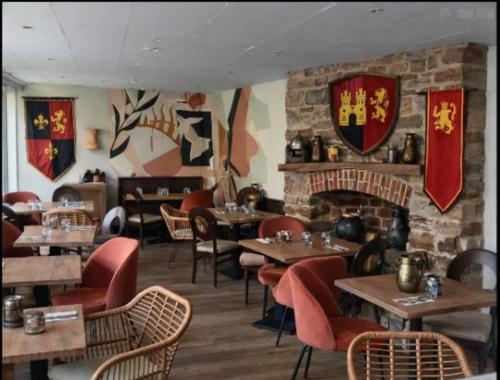 a restaurant with tables and chairs and a fireplace at Auberge de la Poterne in Moncontour