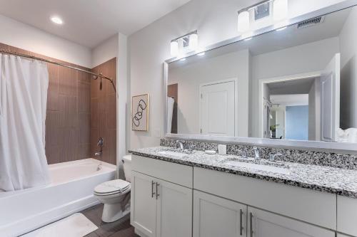 a white bathroom with a tub and a toilet and a sink at Landing Chic 1BD Gym Rooftop Lounge in Orlando