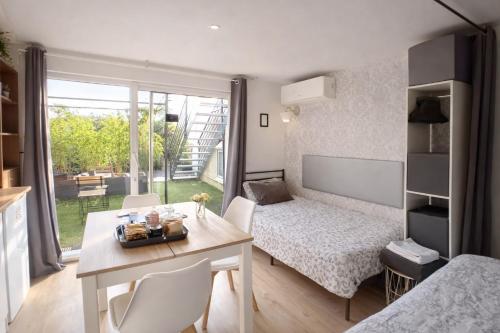 a small room with a table and a bed and a desk at Le Clos Lassagne -Terrasse privative - Climatisation - Lyon Sud - Brignais in Brignais