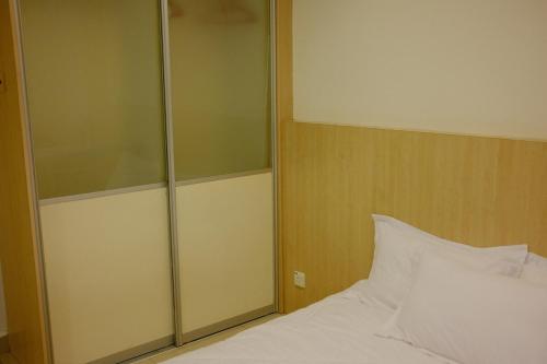 a bedroom with a white bed and a glass cabinet at UrbaNest in Kota Bharu