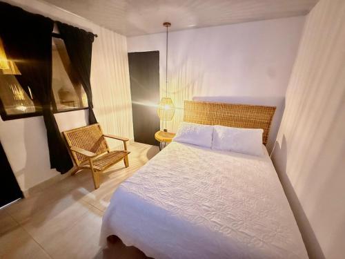 ein Schlafzimmer mit einem weißen Bett und einem Stuhl in der Unterkunft Toba hotel in Ibagué