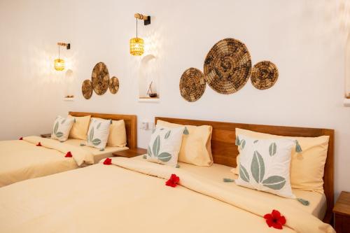 two beds in a room with red flowers on them at OMNYA Nungwi Boutique Hotel in Nungwi