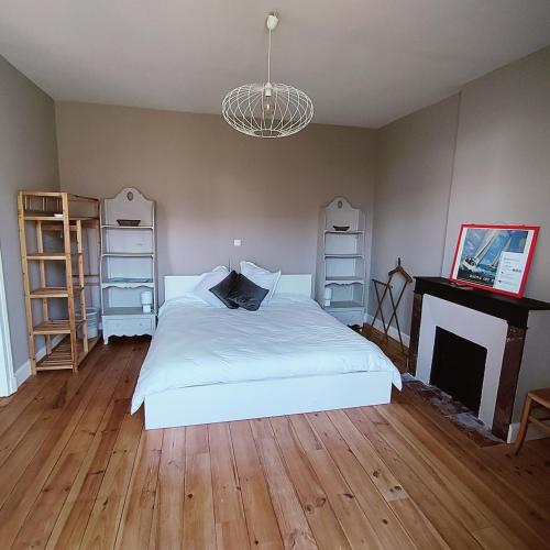 a bedroom with a white bed and a fireplace at Le coin tranquille in Rodez