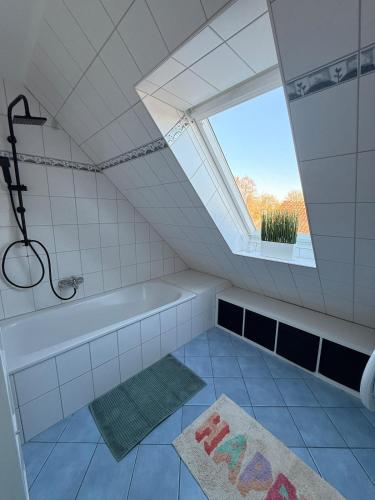a bathroom with a bath tub and a window at Gemütliche Galeriewohnung im Grünen in Trappenkamp