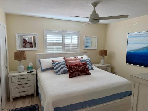 a bedroom with a bed with pillows and a ceiling fan at Birdsong Beachfront Condo in St. Pete Beach