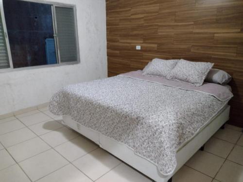 a bed in a white room with a window at Mar e sol in Itanhaém