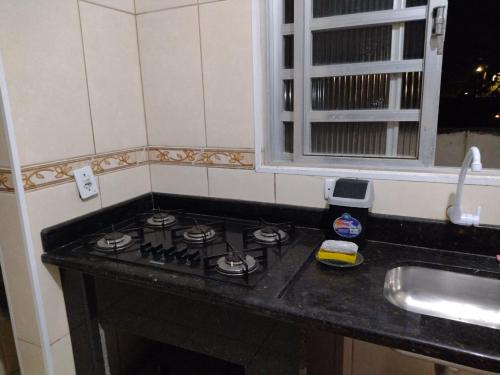 a kitchen counter with a stove and a sink at Mar e sol in Itanhaém