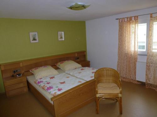 a bedroom with a bed and a chair and a window at Ferienwohnung Neifer in Bad Überkingen