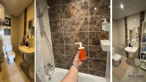 a man holding a bottle of orangeoxide in a bathroom at Modern 2BR Duplex in New Cairo Quiet Area, Balcony & Fast WiFi in Cairo