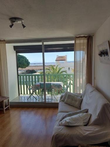 a living room with a couch and a view of a balcony at Le Grand Large in Gruissan