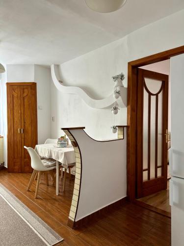 a dining room with a white table and a table and a door at Cozy Apartment D&D in Topliţa