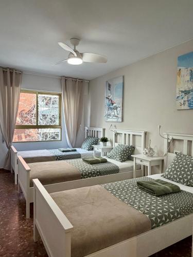 a bedroom with three beds and a ceiling fan at Apartamento Tibi - centro de Gandia in Gandía