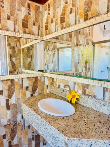 a bathroom with a sink with a flower on a counter at Casa Adriê in Itacaré