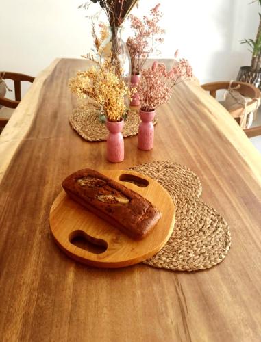 a wooden table with a cutting board with a loaf of bread at Maison Mahana in Bonifacio