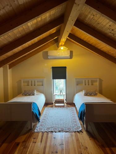two beds in a room with wooden floors at A Casa do Soito in Oliveira do Hospital