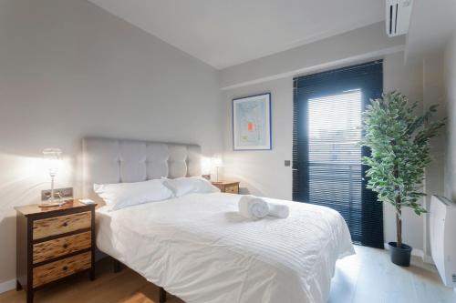 sypialnia z białym łóżkiem z rośliną i oknem w obiekcie Luxury II w Madrycie