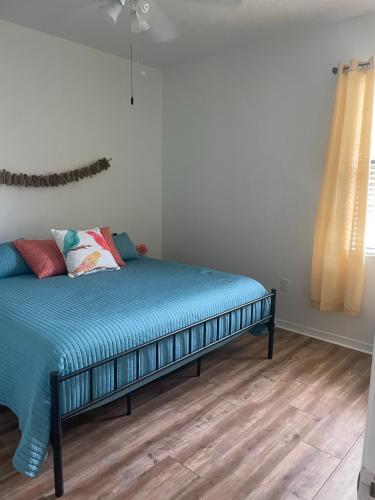 a bedroom with a bed with blue sheets and a window at Loft à louer in Apollo Beach