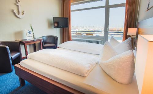 a hotel room with a bed with a large window at Hotel Restaurant Seestern in Heiligenhafen