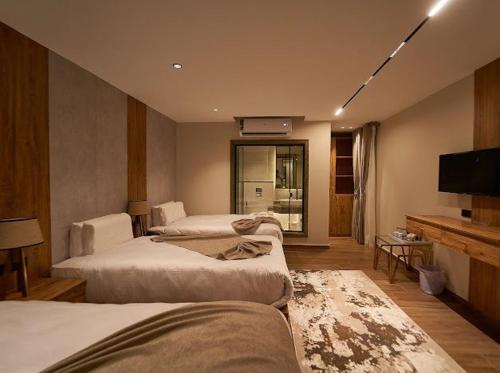 a hotel room with three beds and a television at Gold's Pyramids Hotel in Cairo