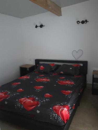 a bed with a black comforter with red hearts on it at love room les plaisirs partagés in Arles