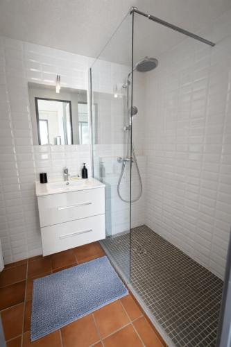 a white bathroom with a shower and a sink at Mazet avec piscine collective in Le Lavandou