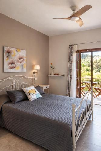 a bedroom with a large bed with a ceiling fan at Nikos & Vivi Studios in Perivólion