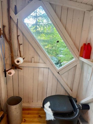 a small attic room with a window and a trash can at Nordic Experience Nuuksio Sauna in Nuuksio